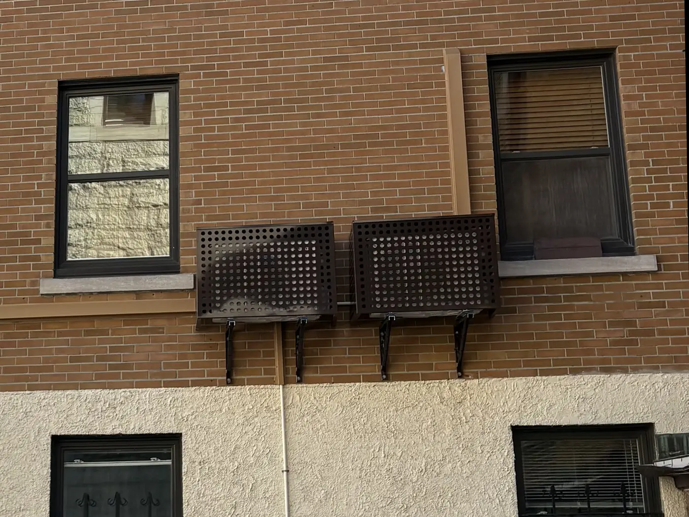 Après : deux thermopompes murales protégées par des boîtiers noirs, lignes dans des goulottes couleur brique