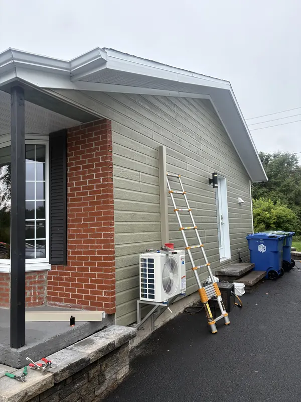 Thermopompe sur support à côté de l'entrée d'un bungalow