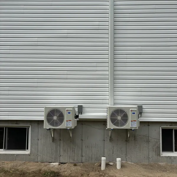 Deux unités extérieures fixées sur supports sous un revêtement gris