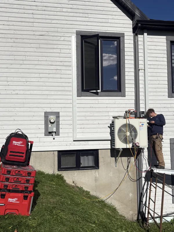 Frigoriste sur une échelle raccordant une thermopompe murale