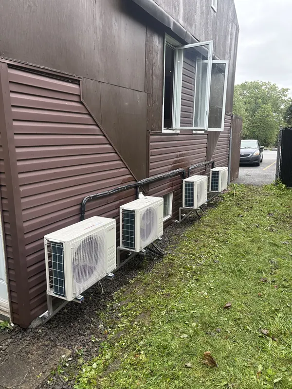 Quatre unités extérieures alignées sur le côté d'un immeuble