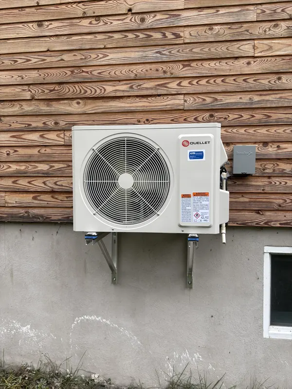 Thermopompe murale sur support, contre un revêtement de bois