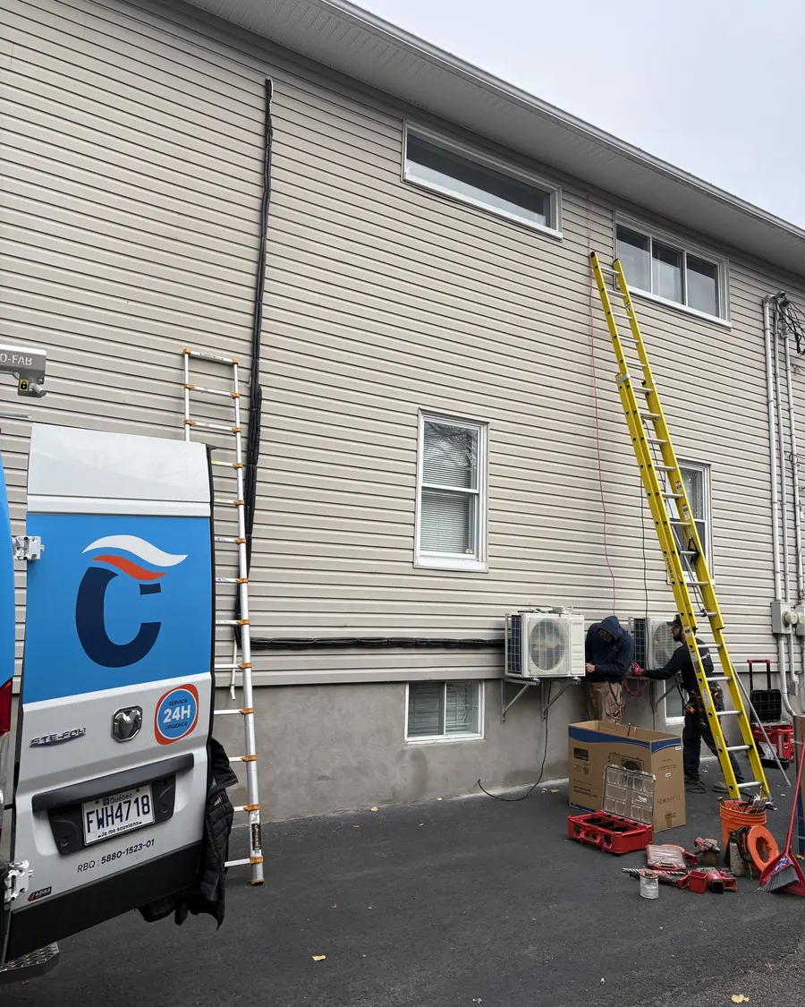 Équipe Climativ installant plusieurs unités sur un grand bâtiment, camion de service à côté