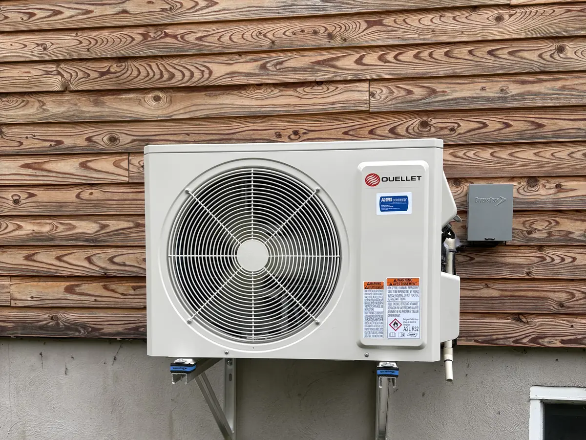 Thermopompe murale neuve installée sur un support contre un revêtement de bois